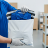 Mitarbeiter im Lager verpackt ein Shirt in eine ECOMAILER® Versandtasche
