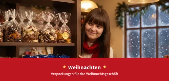 Christmas: female employee in a festively decorated shop next to a shelf with filled clear bags